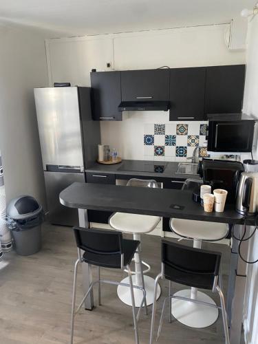 une cuisine avec un comptoir noir et des chaises dans l'établissement T2 Charenton Proche Paris Bercy, à Charenton-le-Pont
