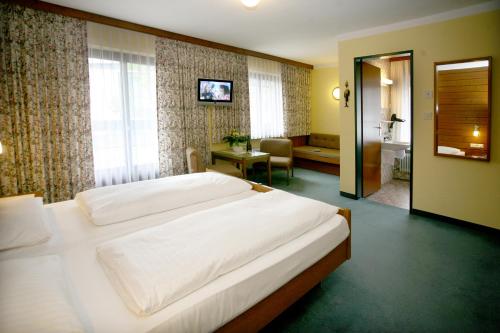 a bedroom with a large white bed and a bathroom at Hotel Restaurant Rössle in Rankweil