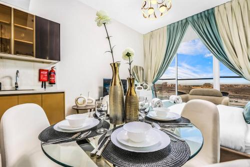 a dining room with a glass table and white chairs at Dubai Studio Retreat Pool, Gym, Balcony & Queen Bed for Two in Dubai