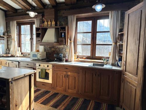 a kitchen with wooden cabinets and a sink and windows at Къща за гости Родопски изгрев in Leshten
