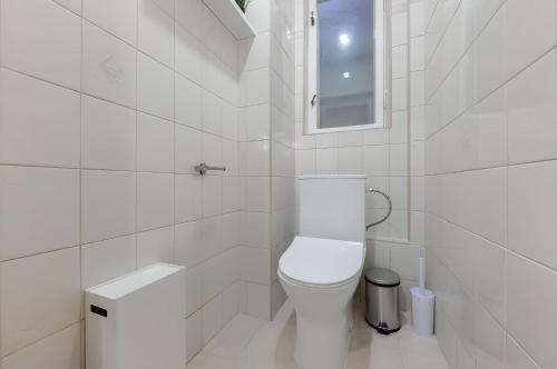Un baño blanco con inodoro y espejo. en Promenade View Apartment, en Karlovy Vary
