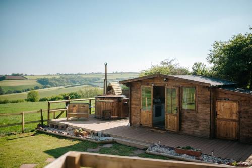 a small wooden house with a deck and a grill at Nirvana Glamping in Tiverton