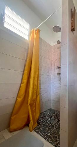 a shower with a yellow shower curtain in a bathroom at Kay Soley La in Saint-François