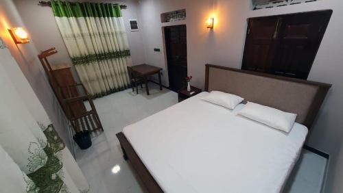 a bedroom with a large white bed with two pillows at Peace Villa - Homestay in Dickwella