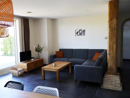 a living room with a blue couch and a tv at Luxe vakantiehuis in Friesland in Joure