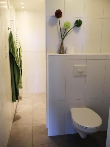 a bathroom with a toilet and a vase with flowers at Luxe vakantiehuis in Friesland in Joure