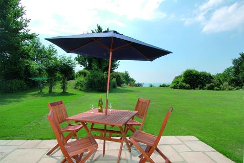 a wooden table and chairs with an umbrella at Woodcliffe Sea-view Apts in Ventnor