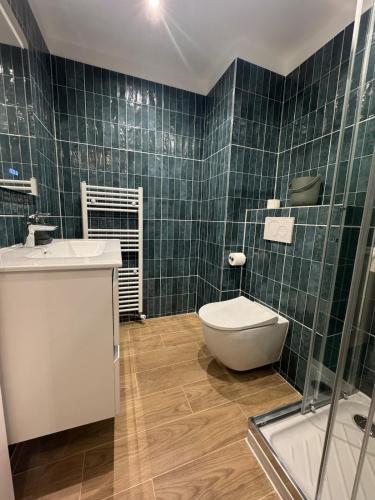 La salle de bains est pourvue de carrelage vert, de toilettes et d'un lavabo. dans l'établissement Studio Calme proche Gare Menton Garavan, à Menton
