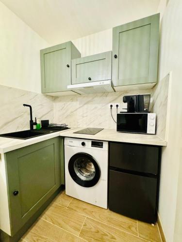 une cuisine avec un lave-linge et un micro-ondes dans l'établissement Studio Calme proche Gare Menton Garavan, à Menton