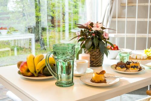 a table topped with plates of fruit and a vase at Domek lubiana180 WABI SABI w lesie jacuzzi sauna kominek - drewno w cenie pobytu - nad jeziorem Kaszuby pieski tylko do 10kg za dodatkową opłatą in Łubiana
