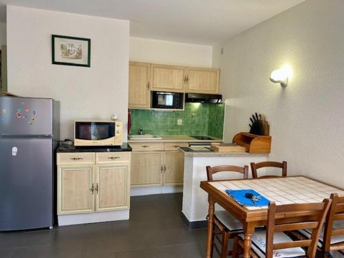 une petite cuisine avec une table et un réfrigérateur dans l'établissement Appartement 5 personnes près plage Nauzan avec terrasse, animaux acceptés - FR-1-494-210, à Vaux-sur-Mer