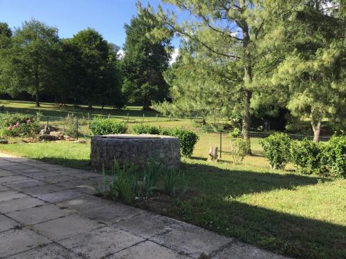 a park with a stone bench in the grass at La maison du bonheur in Milhac