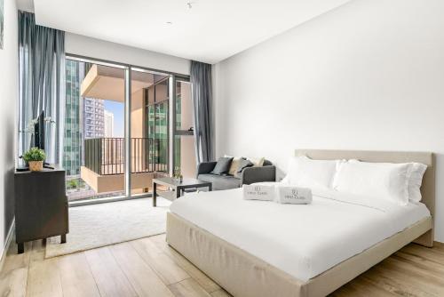 ein Schlafzimmer mit einem großen weißen Bett und ein Wohnzimmer in der Unterkunft Business Bay Studio Near Dubai Mall, Burj Khalifa & Downtown Hotspots in Dubai
