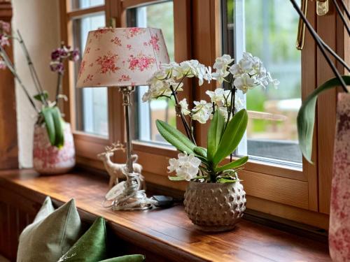 a table with a lamp and flowers on a window sill at Landgasthof & Restaurant Batzenhäusl in Sankt Gilgen