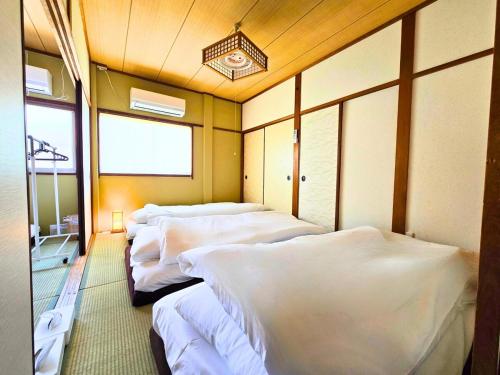 a room with a row of white beds in it at 西九条がてんぼう in Osaka