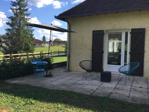 a patio with two chairs and an umbrella at La maison du bonheur in Milhac