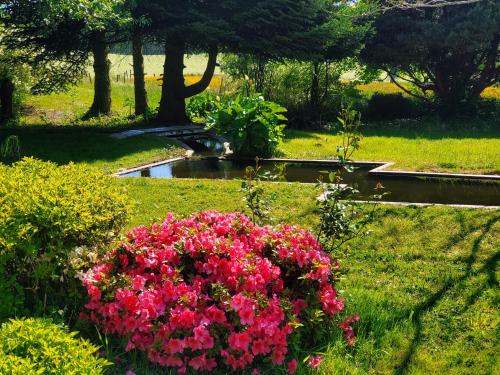 a garden with pink flowers and a pond at Gîte de plain-pied sans escaliers, Dordogne in Firbeix