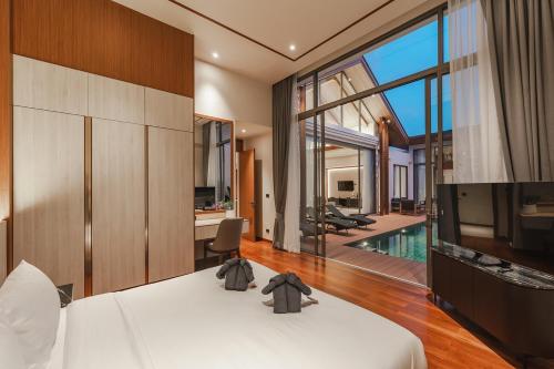 - une chambre avec un lit, une télévision et une piscine dans l'établissement V186 Quiet Glamour Oasis 4BR Poolside Sanctuary, à Laguna Phuket