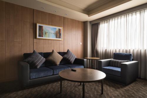 a living room with a couch and two chairs and a table at Fushin Hotel Taipei in Xizhi