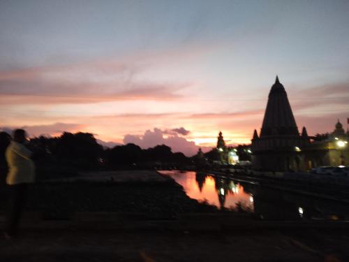 a sunset with a reflection of a building in the water at The Wai Hills MTDC Approved in Wai