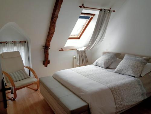 une chambre avec un lit, une fenêtre et une chaise dans l'établissement La Maison du Bonheur, à Mégrit