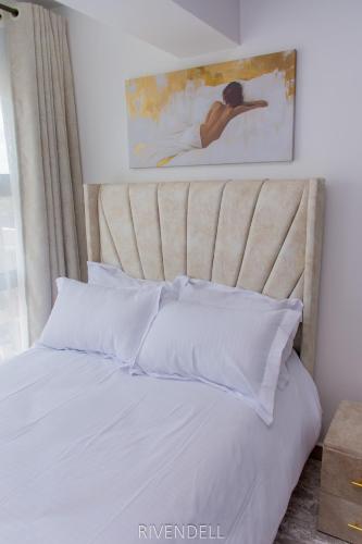 a bed with white pillows and a painting on the wall at Cosy 1BR Apartment along Waiyaki Way, Nairobi in Rungiri