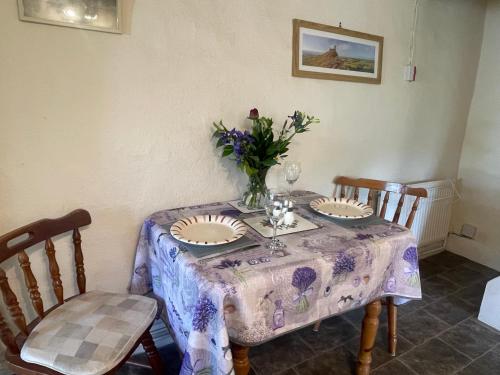 a table with two chairs and a vase of flowers on it at Brentor Self-catering in Brentor