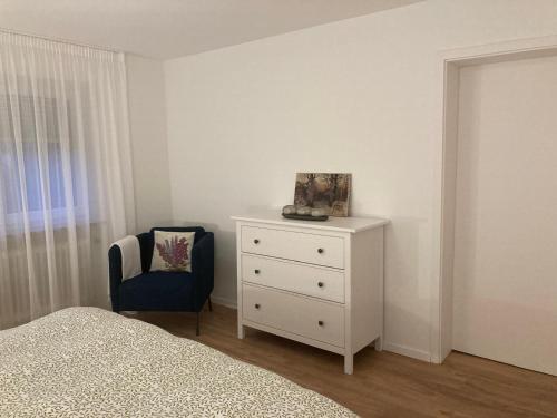 a bedroom with a white dresser and a chair at Geräumige Wohnung bei Basel in Grenzach-Wyhlen