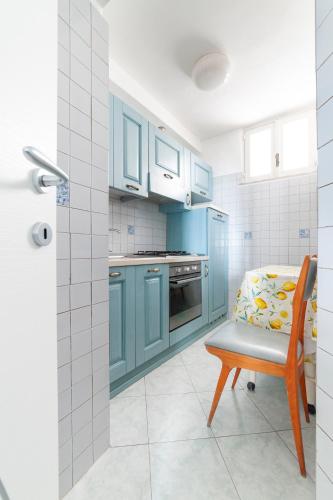 a kitchen with blue cabinets and a chair and a table at Appartamenti Casa del Sole in Ischia