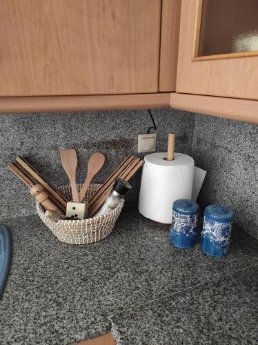a counter with a basket of utensils and a roll of toilet paper at Michaella's apartment in Mytilini