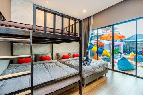 a bedroom with two bunk beds and a slide at Baninlove Beautiful Pool Villa for family in Nikhom Sang Ton Eng Khuan Phet