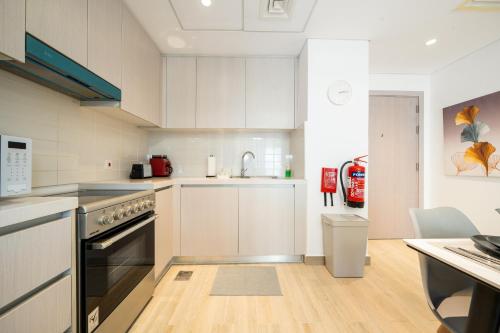 a kitchen with white cabinets and a stove top oven at ZAPBED House - Luxury Holiday Homes in Yas Island in Abu Dhabi