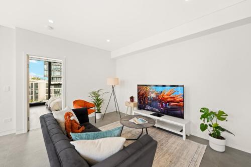 a living room with a couch and a tv at Sydney Olympic Park Escape w Car Space Height 2m in Sydney