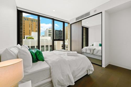 a bedroom with a white bed and a large window at Sydney Olympic Park Escape w Car Space Height 2m in Sydney