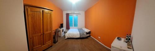 un couloir avec une chambre orange avec un petit lit dans l'établissement chambre chez raissa, à Trappes
