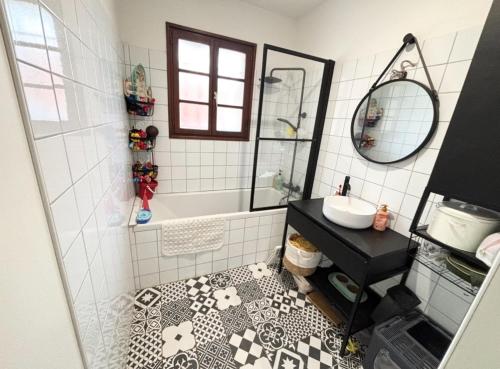 La salle de bains est pourvue de carrelage noir et blanc et d'un lavabo. dans l'établissement Maison calme entre mer et marais, à Longeville-sur-Mer