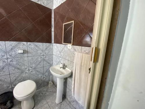 a bathroom with a toilet and a sink at Casa Sobrado com Piscina in Bertioga