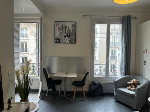 a living room with a couch and a table and two windows at Cosy studio Beaubourg paris centre in Paris