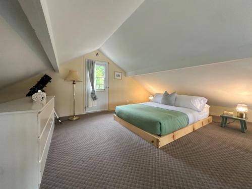 a bedroom with a large bed with a green blanket at Le Mimosa 32 nights min ExitChalets Lake in Morin Heights