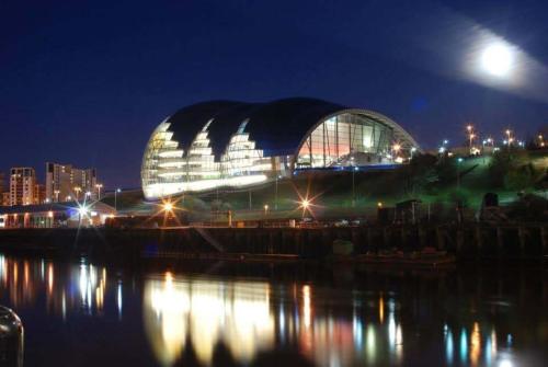 a large glass building at night next to a body of water at Urban Retreat in Newcastle- Pet friendly- Garden in Newcastle upon Tyne