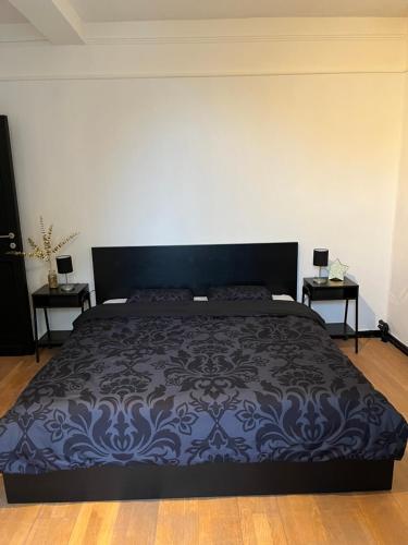 a bedroom with a black bed with two tables at B&B Het Routehuis in Hulshout