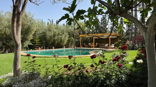 a swimming pool in the middle of a yard with flowers at Dar Tidyan Guest House - Ourika Valley in Igzi Ou Fella