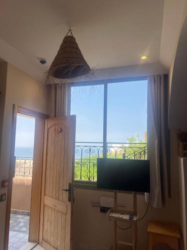 a room with a large window and a television at SurfAppart Morocco in Tamraght Ouzdar