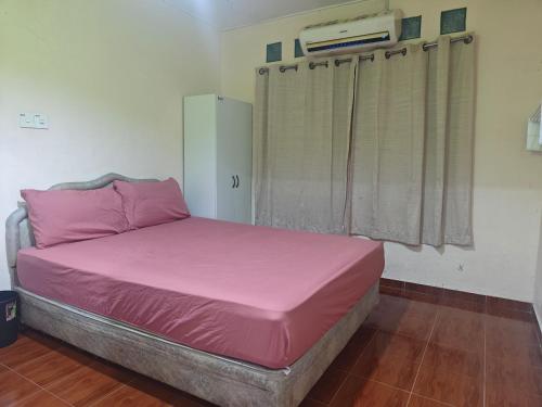 a bed with pink sheets in a room with a window at Warisan Homestay Kampung Chinchin in Jasin