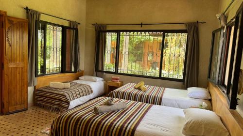 a room with three beds and two windows at Dar Tidyan Guest House - Ourika Valley in Igzi Ou Fella