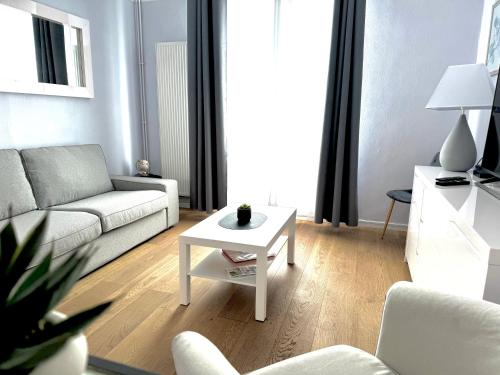 un salon avec un canapé blanc et une table dans l'établissement L'escapade Parisienne, à Maisons-Alfort