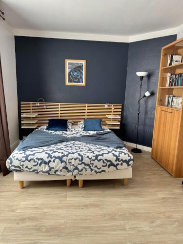 une chambre avec un grand lit aux murs bleus dans l'établissement L'escapade Parisienne, à Maisons-Alfort