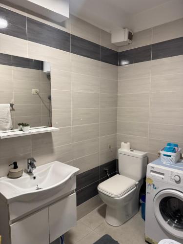 Un baño con inodoro, lavabo y lavadora. en New Ring Apartment, en Tirana