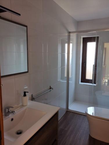 a white bathroom with a sink and a shower at Caticobas in San Pedro