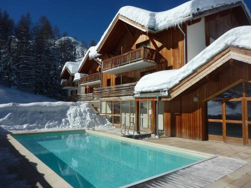 une maison avec une piscine dans la neige dans l'établissement Superbe chalet pour 10 pers. avec piscine, sauna, cheminée, terrasse, skis aux pieds - Les Orres 1800 - FR-1-322-118, aux Orres